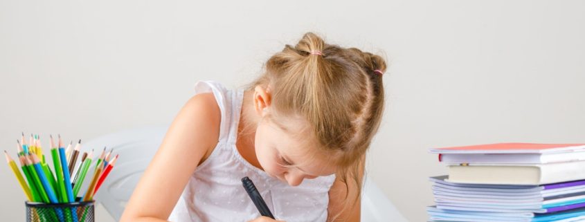 Amakids.bg-MentalnaAritmetika-AnglijskiEzik-GooglePlay-AppStore-education-concept-with-school-supplies-side-view-little-girl-drawing-copybook